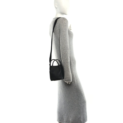 Black micro bale bag on shoulder strap, small grained leather silhouette