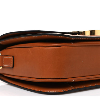 Tan leather crossbody bag showing top closure, gold-tone hardware, and stitched edges.