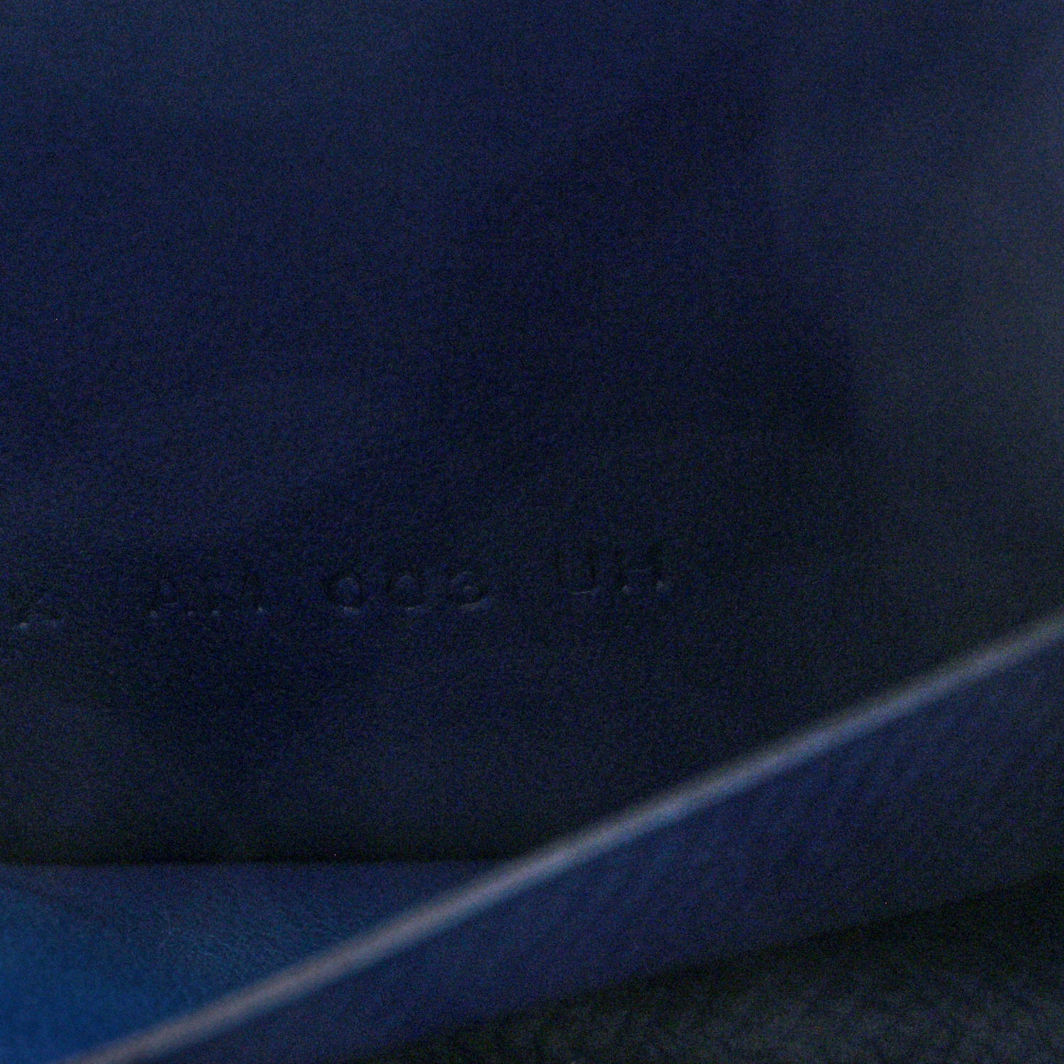 Blue leather slim wallet close-up with faint embossed mark
