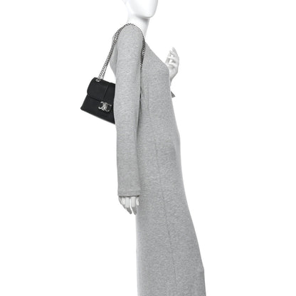 Black leather shoulder bag with chain strap, worn crossbody by model