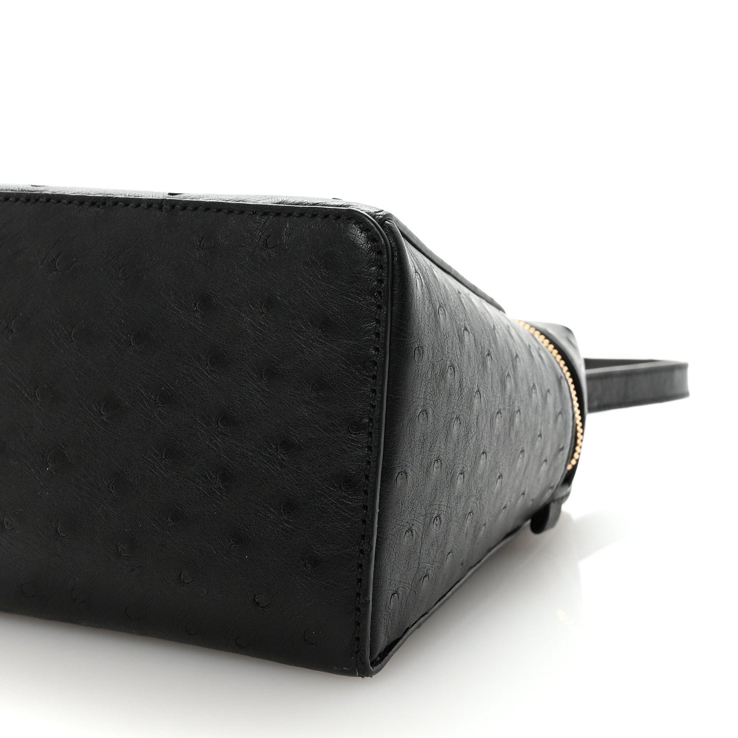 Black ostrich leather mini handbag corner detail with front seam and gold-tone zipper edge