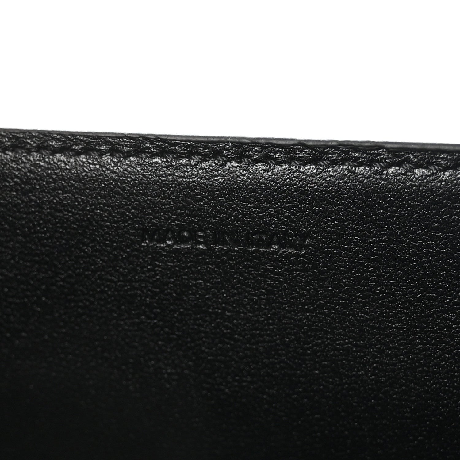 Black leather surface with subtle embossed mark on the bag