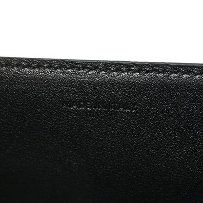 Black leather surface with subtle embossed mark on the bag