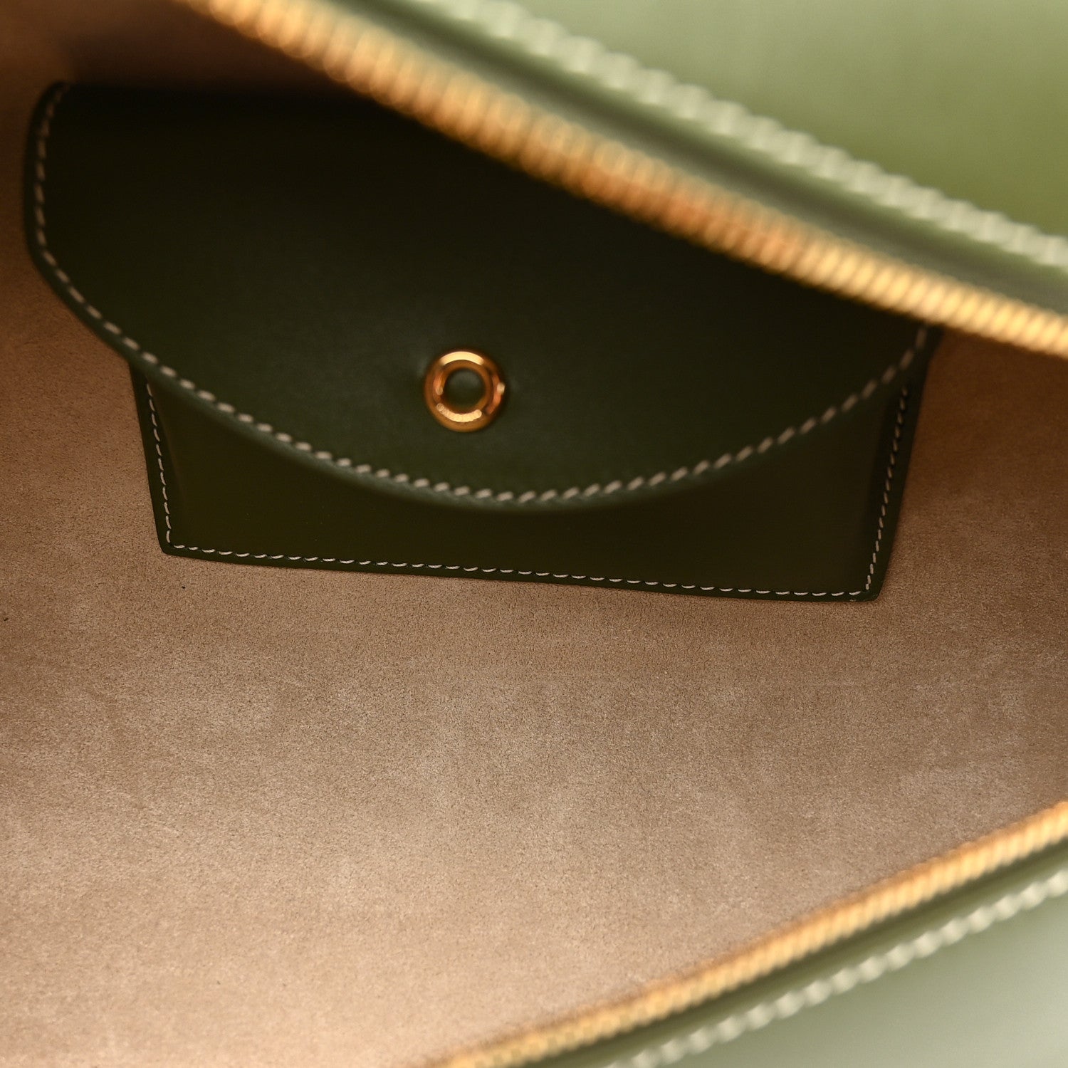 Olive green leather front flap pocket with contrast stitching and small metal ring