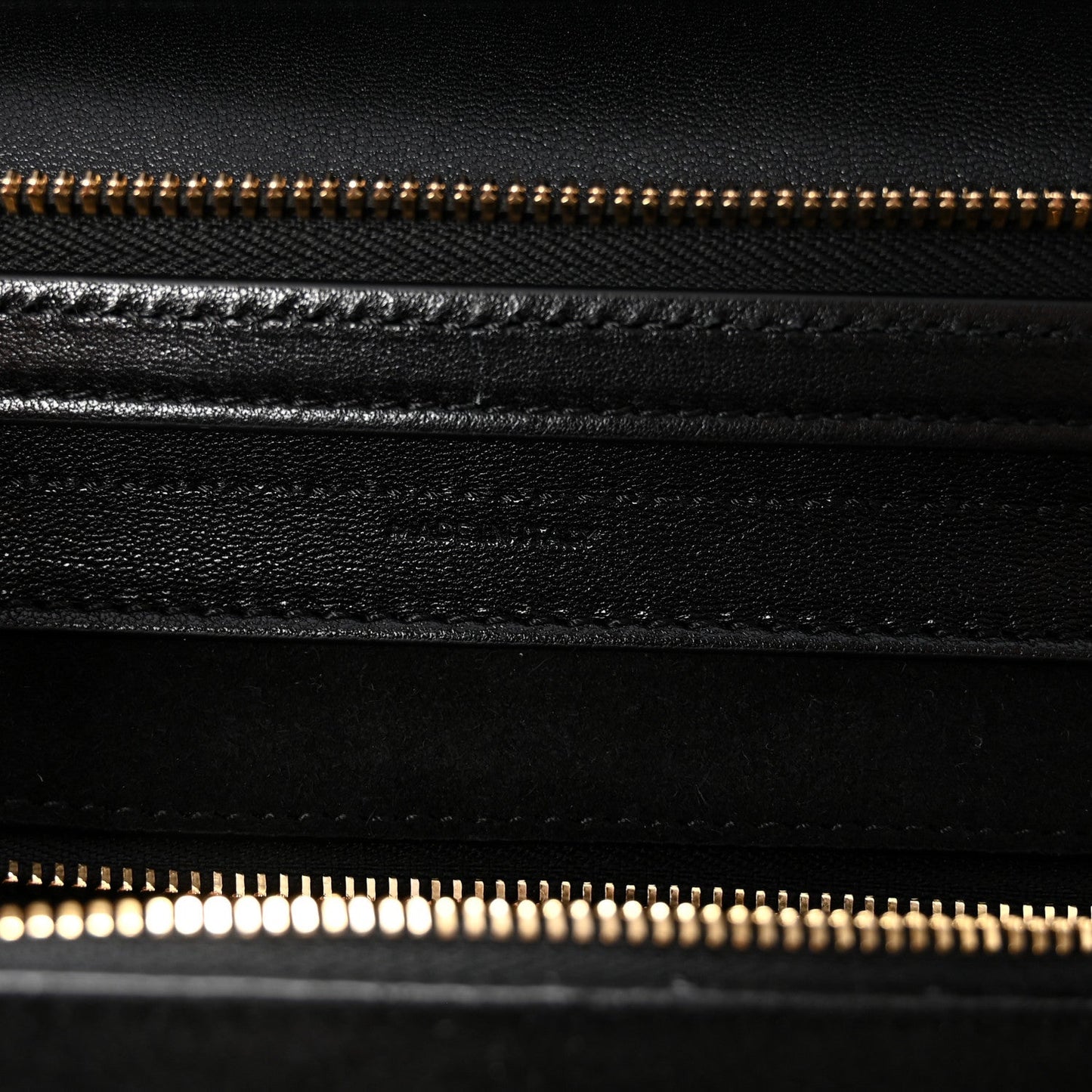 Black leather bag with gold zipper and stitched seam detail.