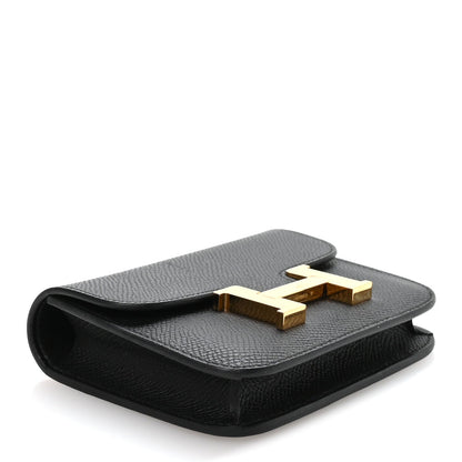 Hermes Constance slim wallet in black with gold H clasp, angled top flap view