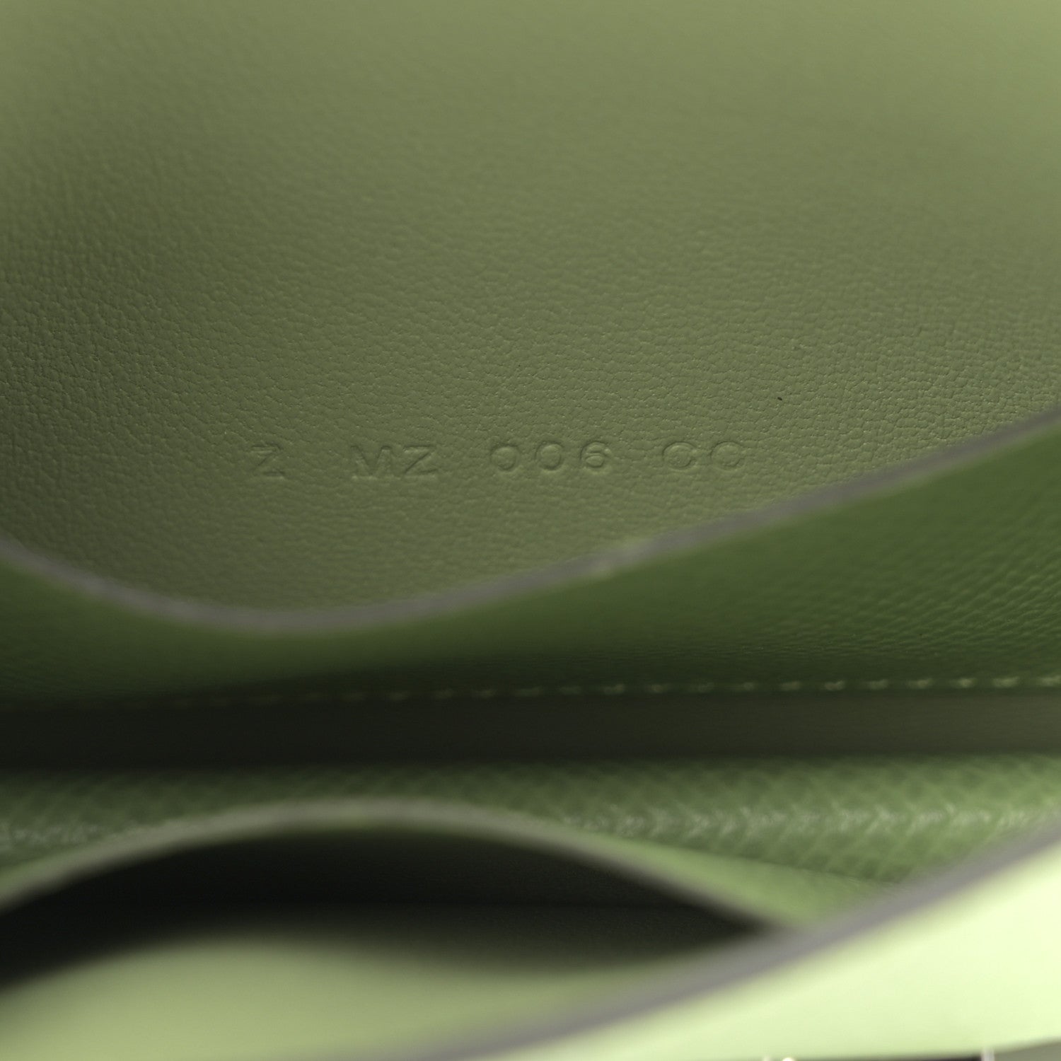 Light green leather wallet close-up of embossed code and stitching