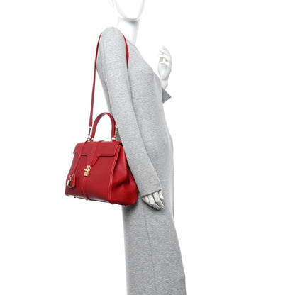 Red leather top-handle bag worn on model, side view with shoulder strap