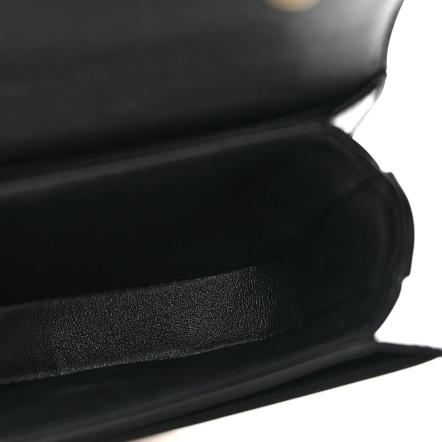 Black shiny mini crossbody bag, close-up of leather texture and curved front