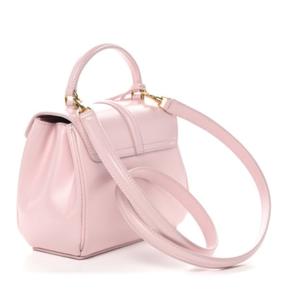Pastel pink mini top-handle bag with flap front and long shoulder strap in gold hardware