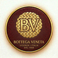 Bottega Veneta logo on a round, brown and gold product with 'BV' initials.